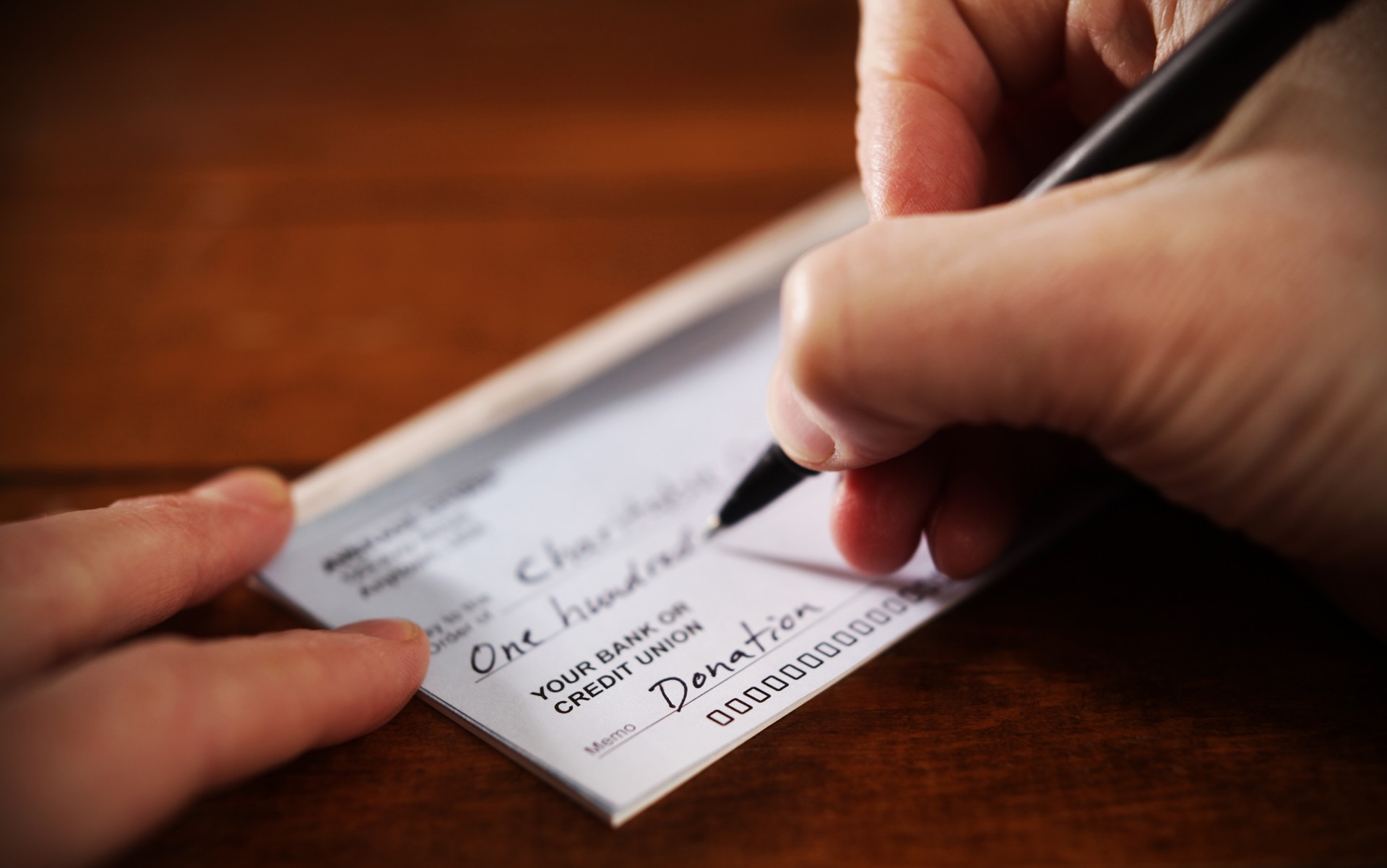 Close up View of Hand Writing A Donation Check